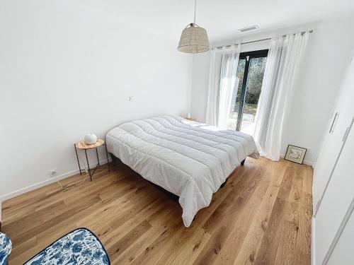 um quarto branco com uma cama e uma janela em Belle maison plain pied à Mougins- 3 chambres em Mougins