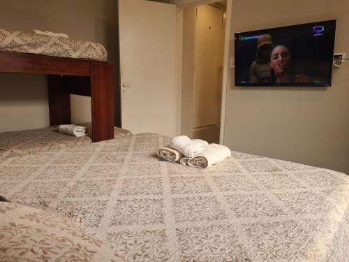 a bedroom with a bed with towels and a tv on the wall at Hotel Firenze in Necochea