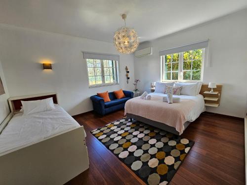 a bedroom with two beds and a couch and a chandelier at Charming Villa Jarros Private pool & Golf in Aroeira