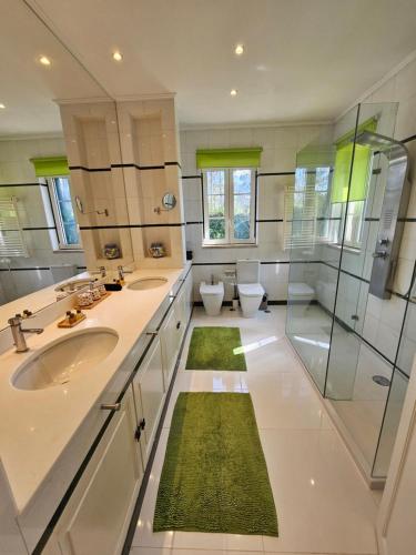 a bathroom with two sinks and a shower and two toilets at Charming Villa Jarros Private pool & Golf in Aroeira