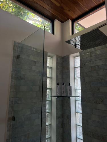 a bathroom with a shower with a glass shower stall at Casa Celajes Sol in Nosara