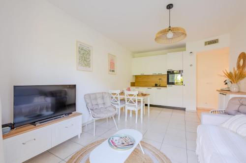 un salon avec un canapé et une télévision dans l'établissement Appartement Lardier - Résidence le clôt des Sarments - Welkeys, à La Croix-Valmer