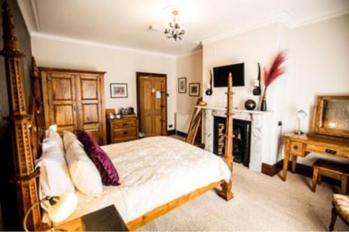 a bedroom with a bed and a fireplace and a television at Abbotsleigh of Whitby in Whitby