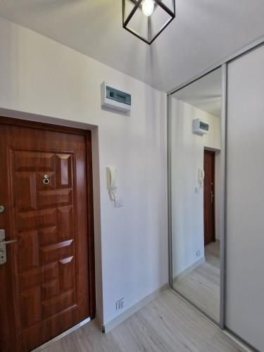 einen Flur mit Spiegel und Tür in der Unterkunft Centrum Apartament in Konin
