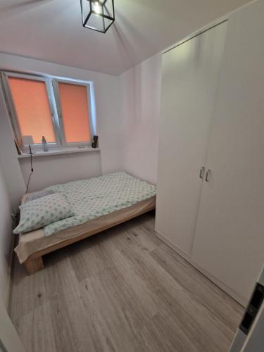ein kleines Schlafzimmer mit einem Bett und einem Fenster in der Unterkunft Centrum Apartament in Konin