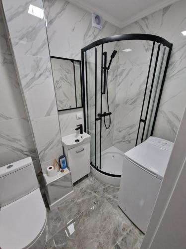 ein weißes Bad mit einer Dusche und einem Waschbecken in der Unterkunft Centrum Apartament in Konin