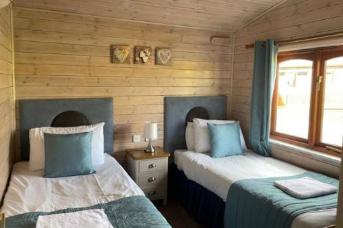 two beds in a room with wooden walls at Campsie Glen Holiday Park in Glasgow
