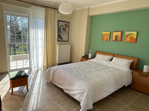a bedroom with a white bed and a large window at Villa Ariadni in Patra