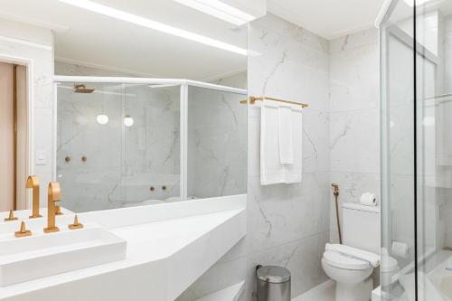 uma casa de banho branca com um chuveiro e um WC. em Brisamar Hotel & SPA São Luís em São Luís