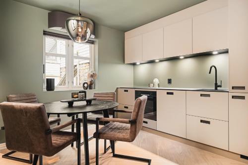 eine Küche mit einem Tisch, Stühlen und einem Waschbecken in der Unterkunft Bryggen // Fløyen Apartments in Bergen