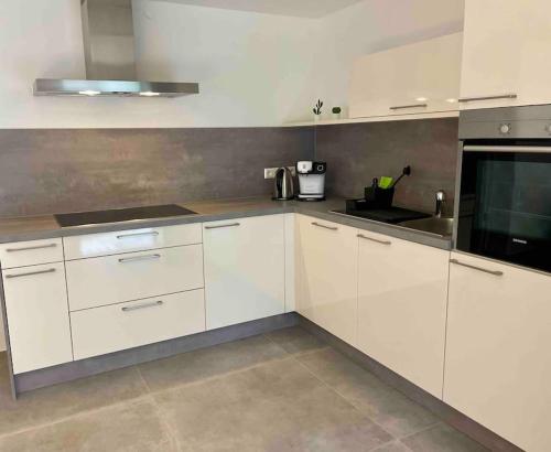 a kitchen with white cabinets and a black microwave at DaCasa-Appartement: zentral/SmartTV/24h Check in in Tamm