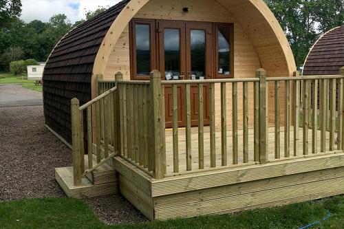 a large wooden cabin with a wooden fence at Campsie Glen Holiday Park in Glasgow