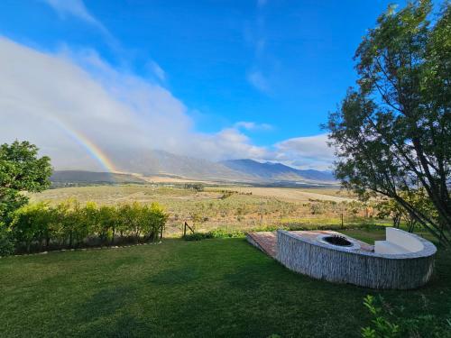 a rainbow in the sky over a field with a fire pit at Valley View Eco Country Estate - Paradise in the Winelands in Villiersdorp