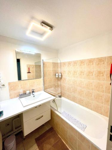 une salle de bain avec un lavabo, une baignoire et un miroir dans l'établissement CHARMANT APPARTEMENT AVEC GRANDE CAPACITÉ D’ACCUEIL, à Saint-Jacques-de-la-Lande