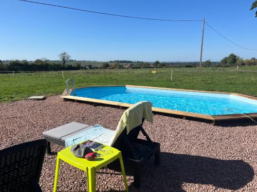 une chaise et une table à côté de la piscine dans l'établissement Maison ancienne Bourgogne piscine privée 7 x 3,5 x 1,30, à Saint-Julien-de-Civry