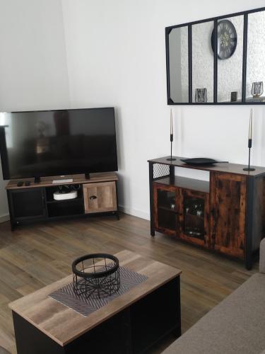 ein Wohnzimmer mit einem Flachbild-TV und einem Couchtisch in der Unterkunft Bienvenue chez Coco in Dunkerque