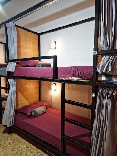 two bunk beds in a room with purple sheets at SEMERU HOSTEL MALANG in Malang
