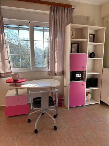 a room with a table and a pink desk and shelves at Villa Ariadni in Patra