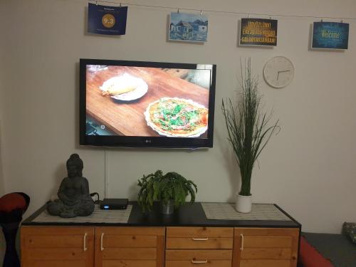 シャルゴータルヤーンにあるGoldapartman Salgótarjánの壁に掛けられたフラットスクリーンテレビとピザ