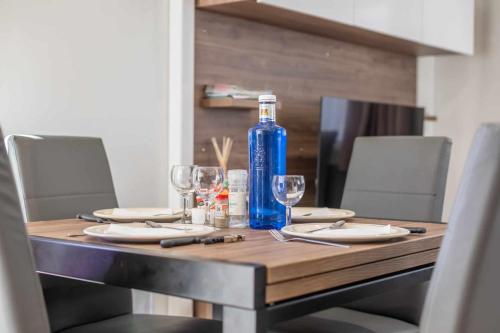 a table with a blue bottle and glasses on it at MOBILHOME SOLEIA NEUF 2023 MAR ESTANG SIBLU VILLAGE Canet-en-Roussillon in Canet-en-Roussillon