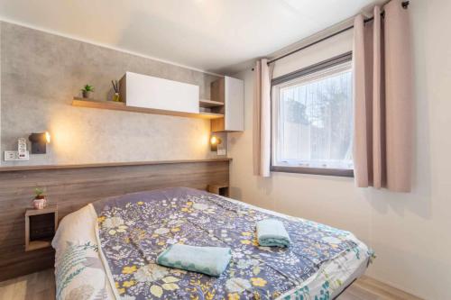 a bedroom with a bed with two pillows on it at MOBILHOME SOLEIA NEUF 2023 MAR ESTANG SIBLU VILLAGE Canet-en-Roussillon in Canet-en-Roussillon