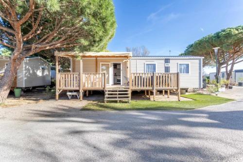 a tiny house with a porch and a tree at MOBILHOME SOLEIA NEUF 2023 MAR ESTANG SIBLU VILLAGE Canet-en-Roussillon in Canet-en-Roussillon