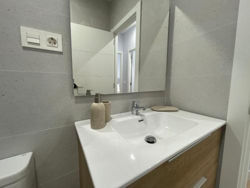 a bathroom with a white sink and a mirror at ByAndreea Apartaments EtxeBi in Guernica y Luno