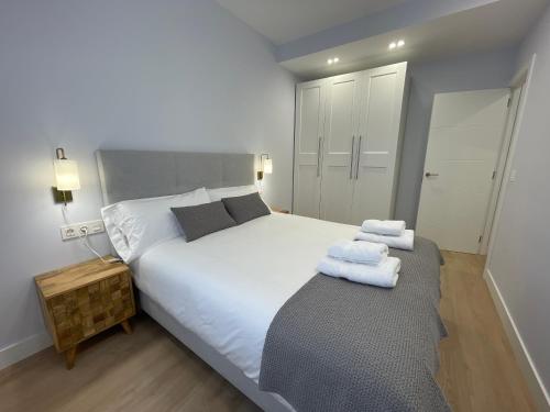 1 dormitorio con 1 cama blanca grande y toallas. en ByAndreea Apartaments EtxeBi, en Guernica y Luno