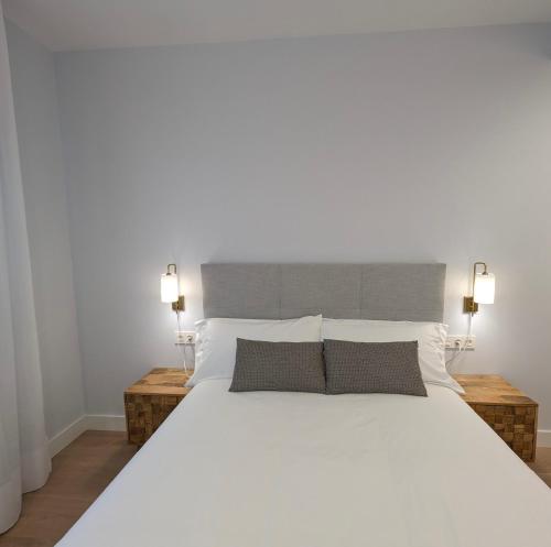 1 dormitorio con 1 cama blanca grande y 2 lámparas en ByAndreea Apartaments EtxeBi, en Guernica y Luno