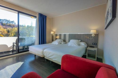 a hotel room with a bed and a red chair at Hotel La Palma de Llanes in Llanes