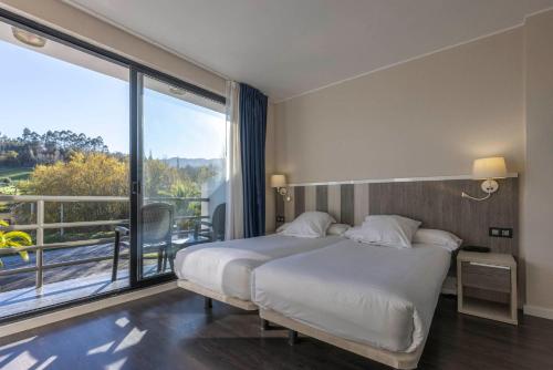 a hotel room with a bed and a large window at Hotel La Palma de Llanes in Llanes