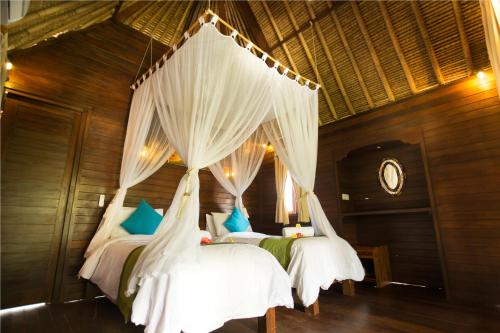 1 dormitorio con 2 camas con cortinas blancas en Sunset Coin Lembongan, en Nusa Lembongan