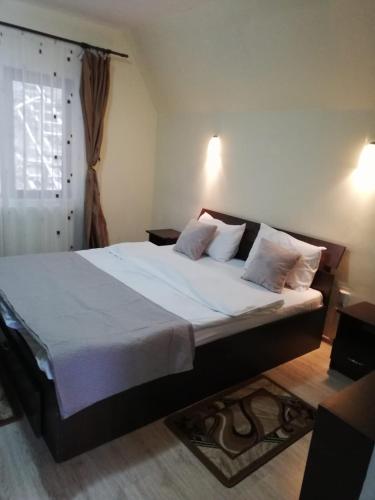 Casa Din Padure في سينيا: غرفة نوم بسرير كبير عليها شراشف ووسائد بيضاء