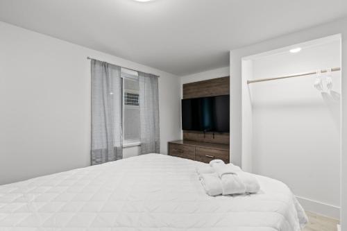 a white bedroom with a large bed and a flat screen tv at Fin's Inn in Myrtle Beach