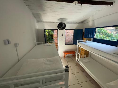 a room with two beds and a clock on the ceiling at Ooxe Hostel in Itacaré