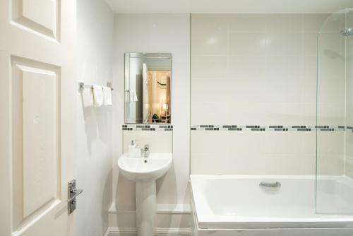 a white bathroom with a sink and a shower at Bucks Luxury Apartment - free parking in Buckinghamshire