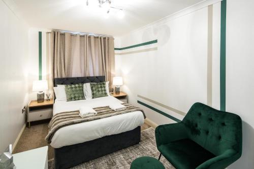 a bedroom with a bed and a green chair at Bucks Luxury Apartment - free parking in Buckinghamshire