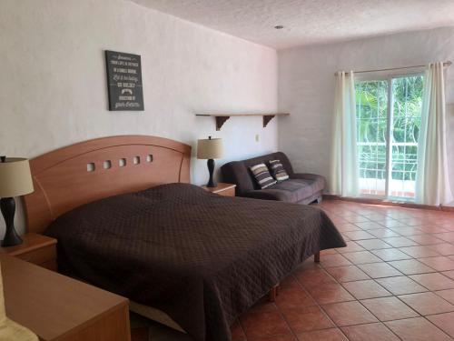 1 dormitorio con 1 cama y 1 sofá en Hermosa Casa llena de vida, jardín y alberca! en Jiutepec