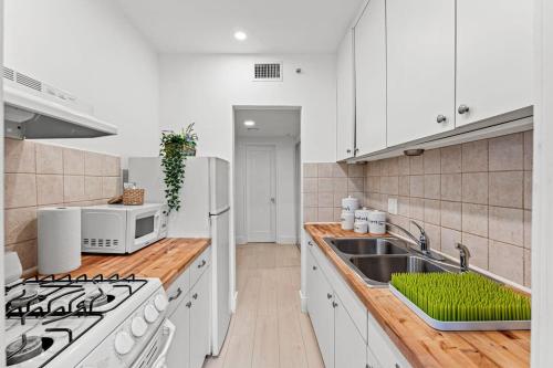 a white kitchen with a sink and a microwave at Beautiful Apt in Victoria Park (Las Olas Blvd) in Fort Lauderdale
