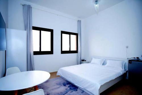 a white bedroom with a bed and a table at Your Silicon Oasis Comfort Haven in Dubai