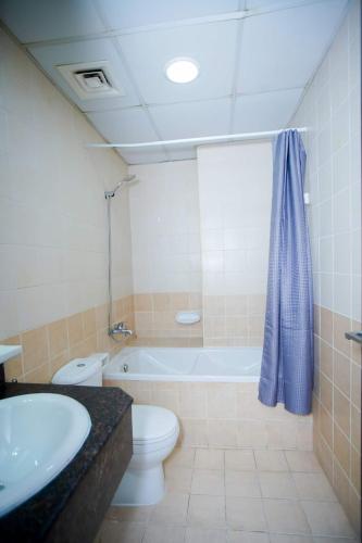 a bathroom with a tub and a toilet and a sink at Your Silicon Oasis Comfort Haven in Dubai