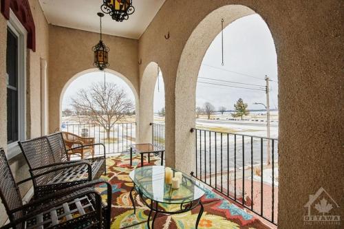 a balcony with arches and a glass table and chairs at Inn By The Park Morrisburg in Morrisburg