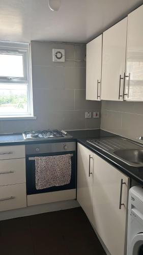 a kitchen with white cabinets and a stove top oven at 43A ground floor apartment in London