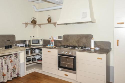 cocina con armarios blancos y fogones en Casa Conforta, en Le Piazze