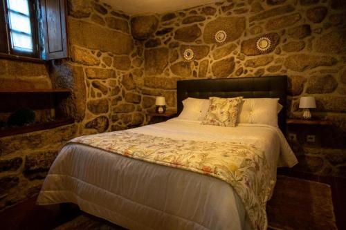 sypialnia z łóżkiem w kamiennej ścianie w obiekcie Casa Do Charco - Peneda Gerês w mieście Geres