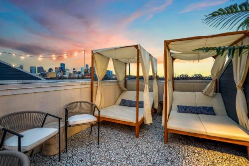 a balcony with two chairs and two canopy beds at The Green Haus: Luxxe Cabana Rooftop Retreat in Houston