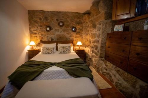 sypialnia z łóżkiem w pokoju z kamiennymi ścianami w obiekcie Casa Do Sertão - Gerês w mieście Geres