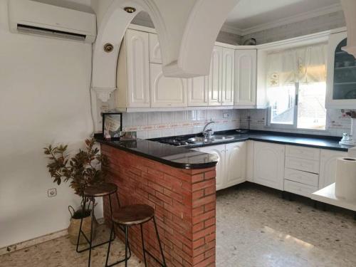 a kitchen with white cabinets and a brick counter and stools at Bonita casa en Sevilla in San Pablo