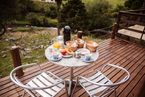 una mesa con desayuno y bebidas en la terraza en Recanto das Águas - Urubici - SC, en Urubici