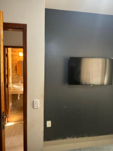 TV de pantalla plana en una pared junto a una puerta en Serra Mar Suítes,Lofts, e casas à 300 metros das praias, en Arraial do Cabo